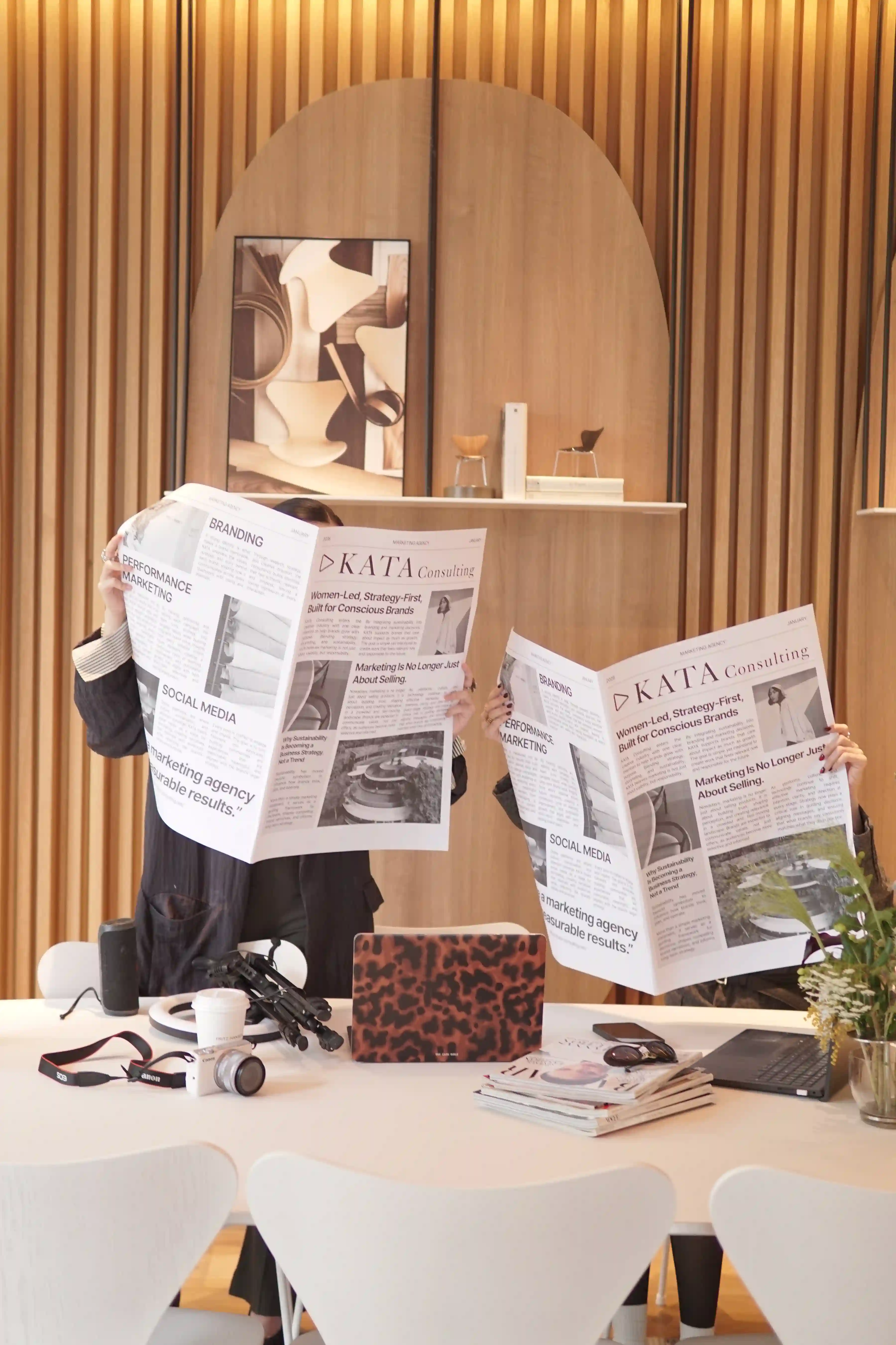 Three KATA team members holding laptops, one in sunglasses, during the brand content shoot